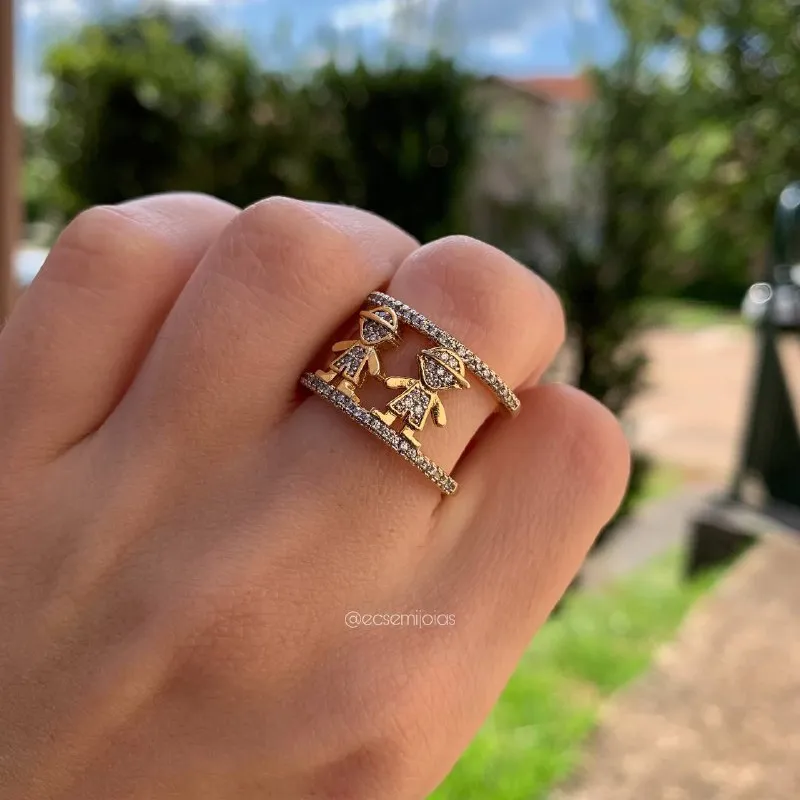 Anel c/ duas crianças cravejadas, dois meninos - banhado a ouro 18k