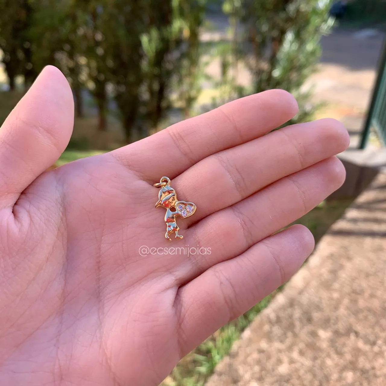 Pingente menino de lado segurando coração cravejado - banhado a ouro 18k