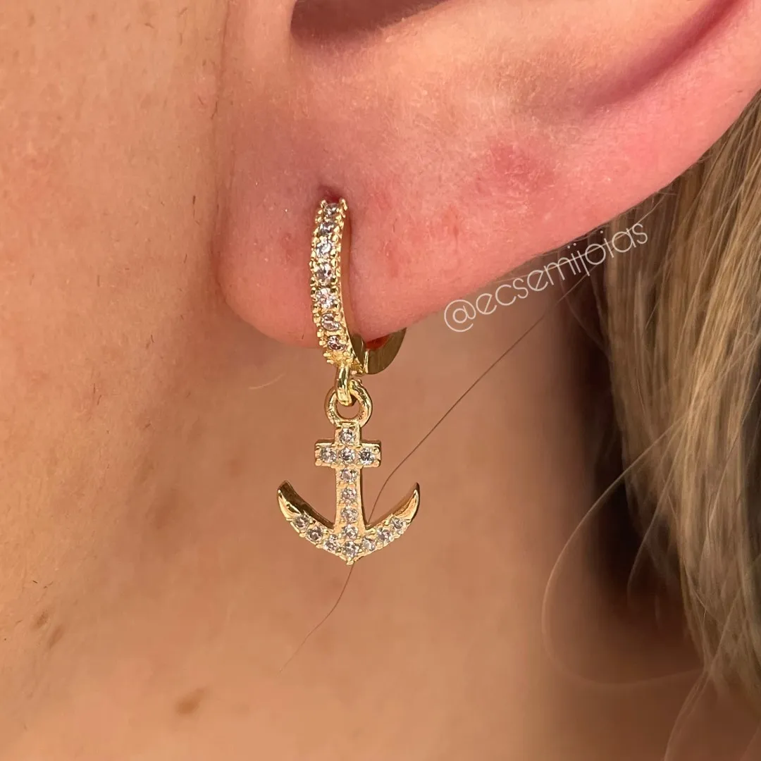 Argola tranqueta com 1 fileira cravejada e pingente de âncora cravejada - banhado a ouro 18k