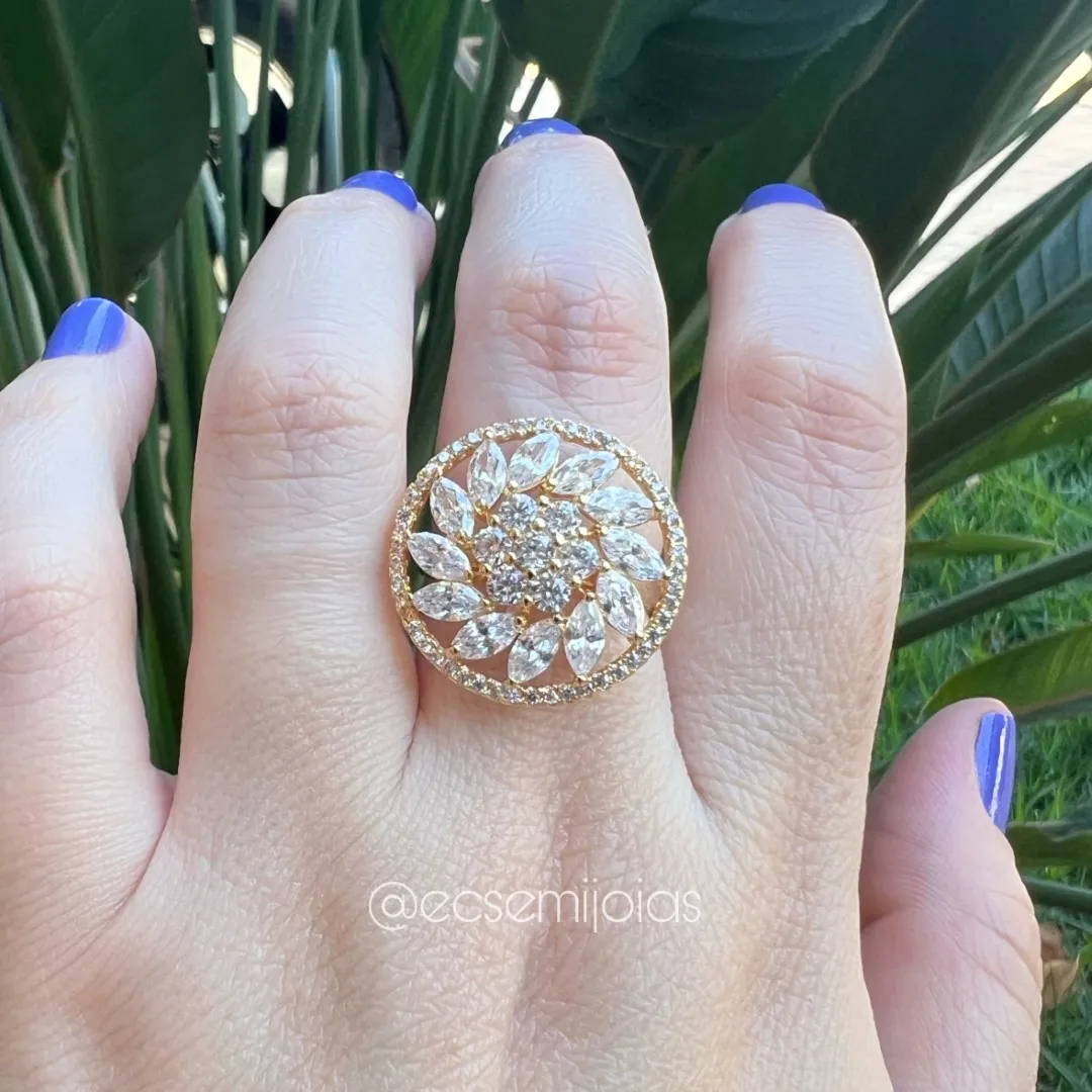 Anel redondo com zircônias maiores no centro, com fileira de navetes em volta e cravejado nas bordas - banhado a ouro 18k