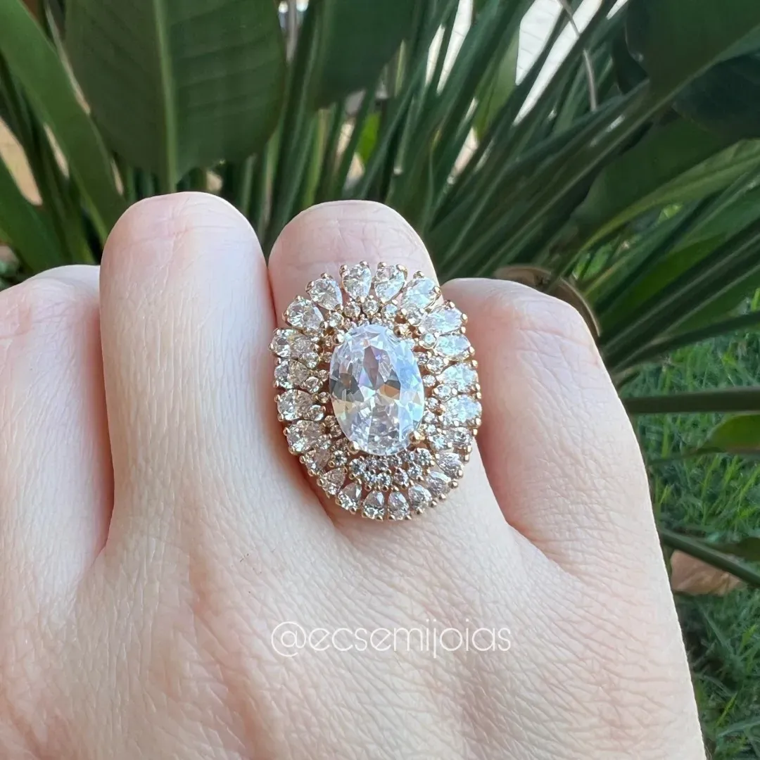 Anel oval, com zircônia grande no centro, cravejado em volta e bordas com gotas grandes e pequenas - banhado a ouro 18k
