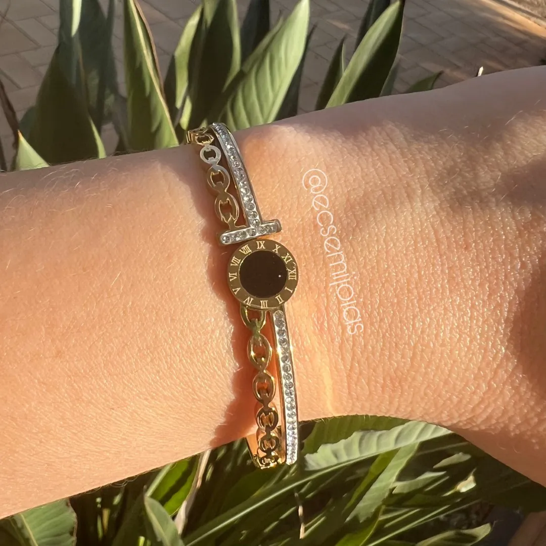 Bracelete com pedra redonda no centro com borda com números gregos e aro cravejado e elos vazados - aço dourado