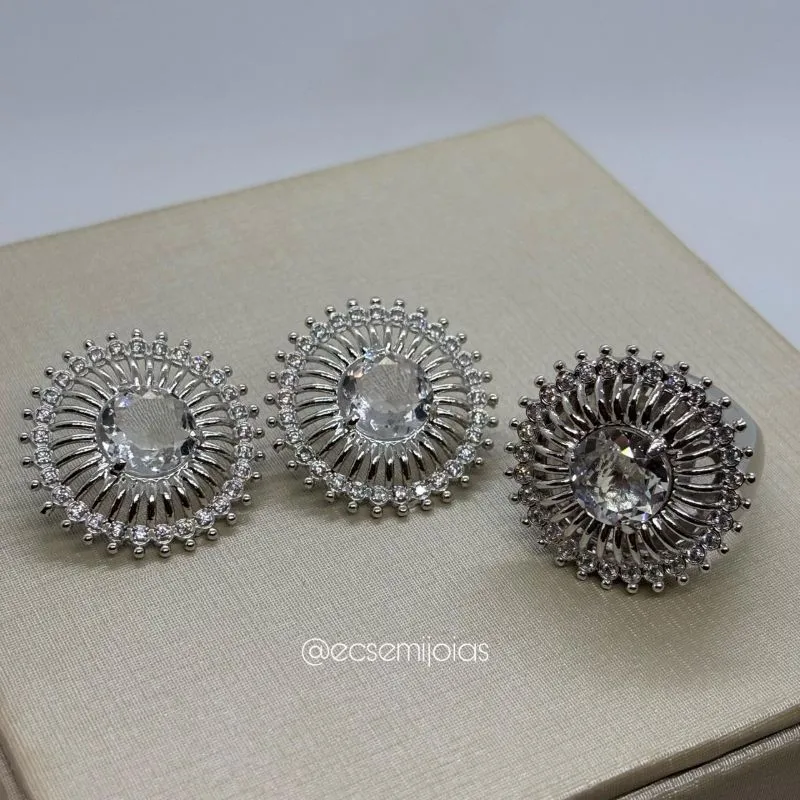Conjunto de anel e brinco redondo com zircônia maior no centro, aro lateral vazado e borda cravejada - banhado a ródio branco
